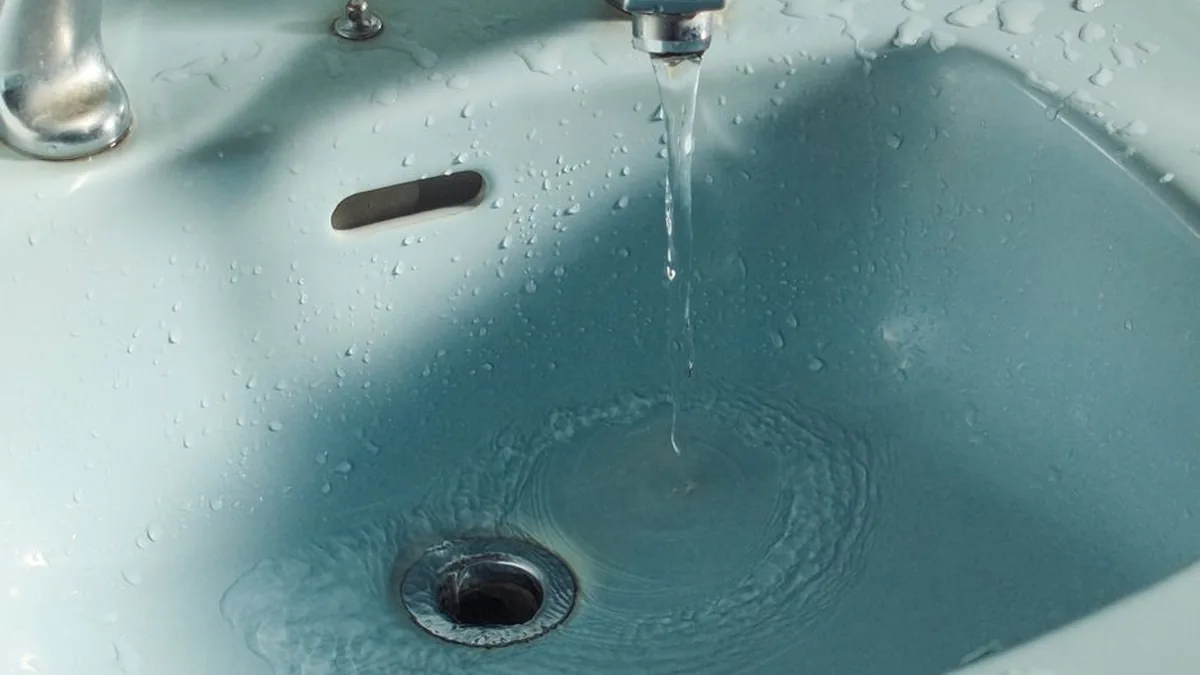 Water pooling in a basin around the plughole while the tap runs